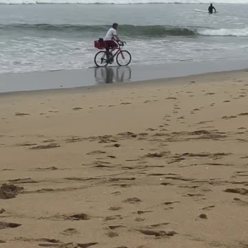 Person riding bike through beach wet sand