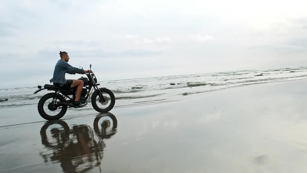 Tracking shot of a wanderlust riding a motorbike at the beach