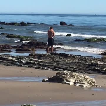 Guy on the beach playing a trombone for the ocean