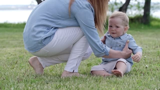 a mother training her young child to walk in the grass the park