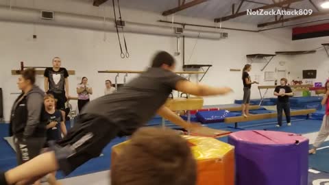 Green shirt kid jumps into foam gymnastics cylindars