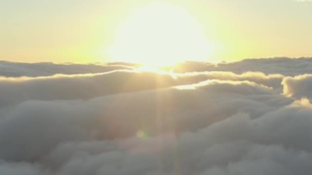 The sun setting on the horizon of a cloudy mountain range