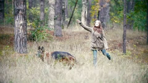 Young woman throwing a stick away at her dog