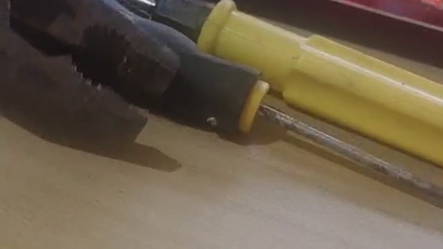 Clamp the screwdriver with the pliers