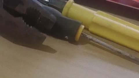 Clamp the screwdriver with the pliers