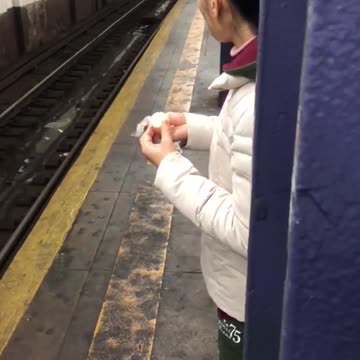 Woman white jacket eating egg subway platform
