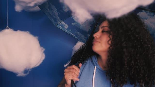 Conceptual portrait of a girl with umbrella with clouds