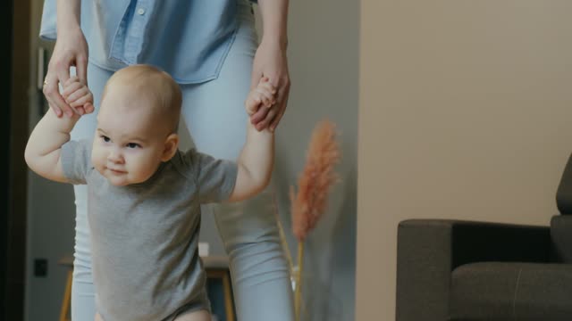 The baby begins to walk with his beautiful mother.