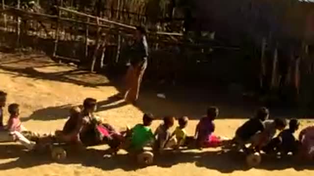 A make shift train of several kids riding down dirt hill