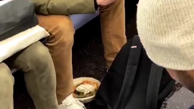 Guy sets his bowl of food on subway floor to text on his phone