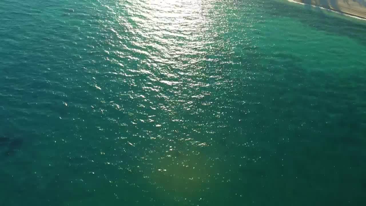 Flying over the azure blue water of a beach