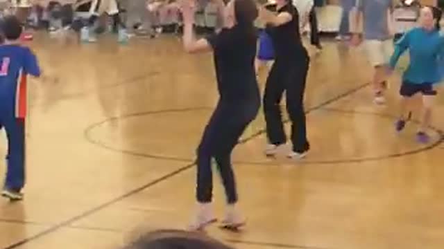Girl in black misses basketball pass and then falls face first onto floor