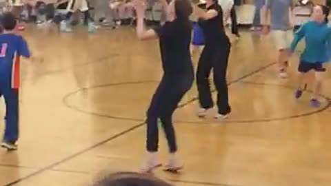 Girl in black misses basketball pass and then falls face first onto floor