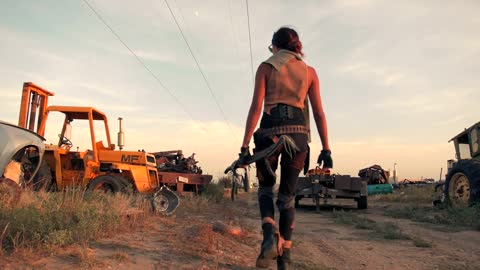 A woman with a sword walking through the scrapyard