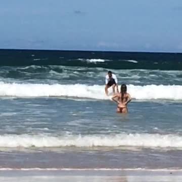 White shirt guy slowly rides surfboard nowhere and falls off