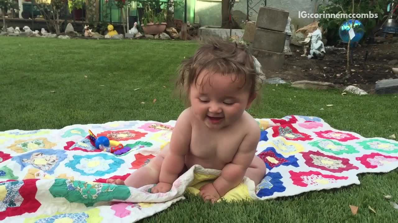 Blue ball thrown at baby sitting on grass