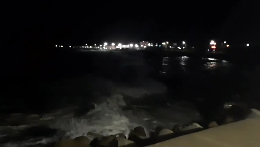 Waves crashing on the breakwater at night