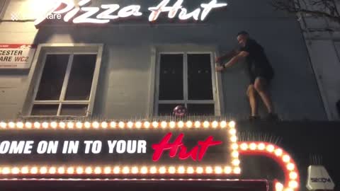 Fearless football fan climbs on top of pigeon spikes on restaurant to retrieve a ball