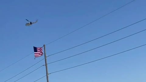 A helicopter with a huge American flag accompanies the convoy of truckers and citizens.