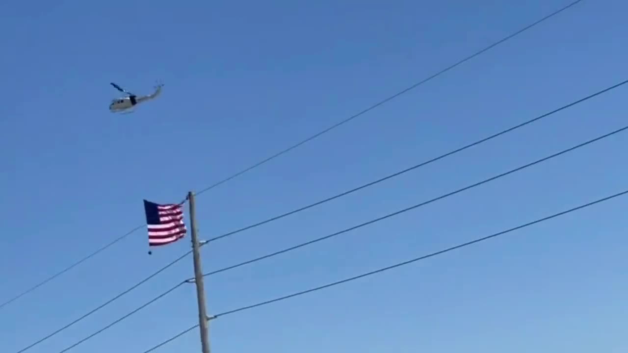 A helicopter with a huge American flag accompanies the convoy of truckers and citizens.