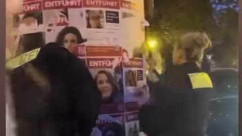 German police officers destroying poster of Israeli civilians kidnapped by Hamas.