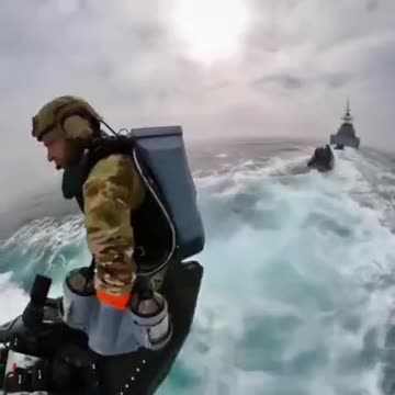 Marines perform boarding exercises with jetpacks and land on a high-speed ship