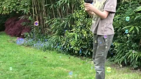 Kid Plays With Bubble Gun in the Backyard