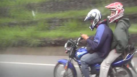 Costa Rica Kid on Motorcycle with friend on back is texting as he drives.