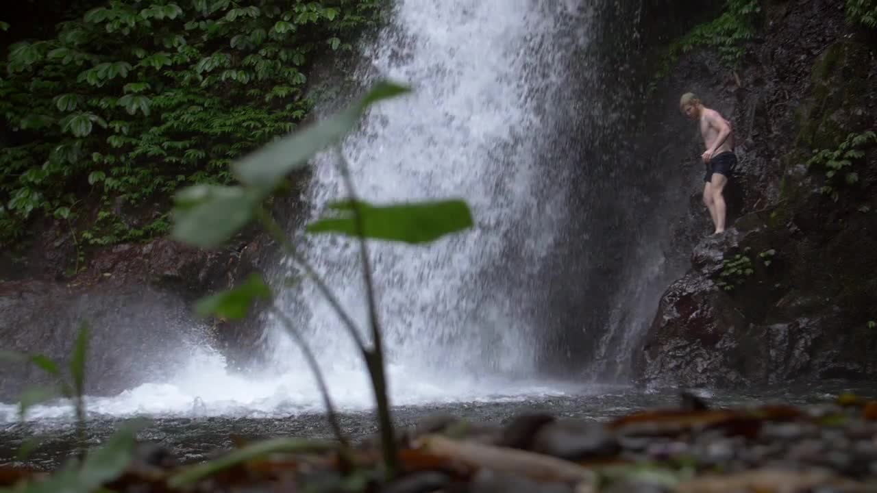 Man on a Ledge by a Waterfall