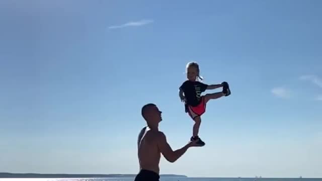 Dad Tosses Toddler And Balances Her on His Hand At Beach