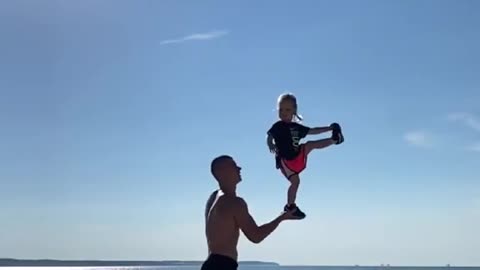 Dad Tosses Toddler And Balances Her on His Hand At Beach