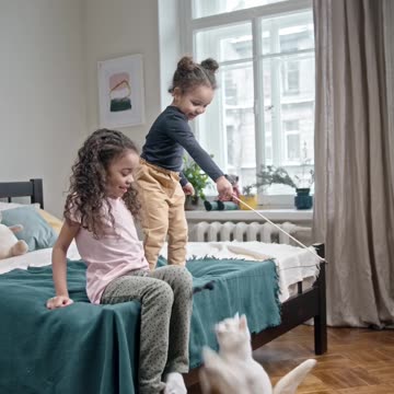 Kids Playing Catch The Bait With Their Cat In The Bedroom