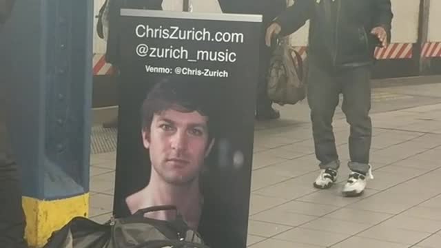 Guy in black jacket dances next to subway singer