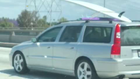 Grey silver car carrying white surf board