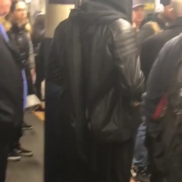 Guy in hoodie wears samurai sword in subway terminal