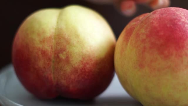 Person Arranging Plate of Peaches