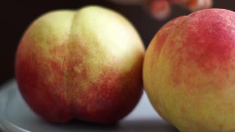 Person Arranging Plate of Peaches