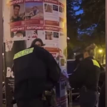 German police officers destroying poster of Israeli civilians kidnapped by Hamas.