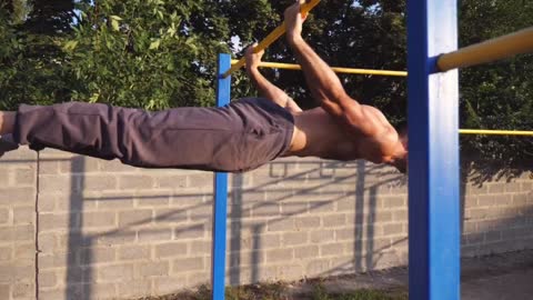 STRONG YOUNG MAN DOING STUNTS ON A HORIZONTAL BAR