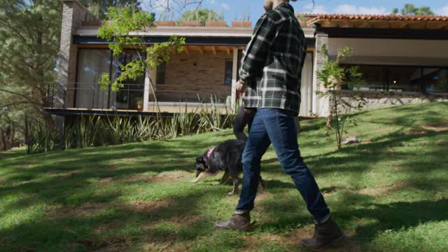 Man and woman walking a dog in a garden