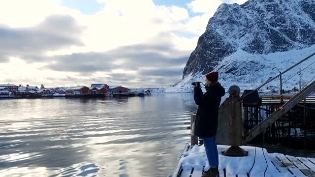 a woman taking a photo of a snowy mountain