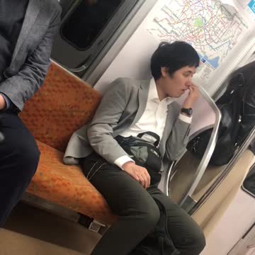 Man in grey blazer white shirt picking nose on train
