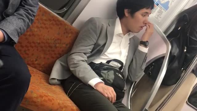 Man in grey blazer white shirt picking nose on train