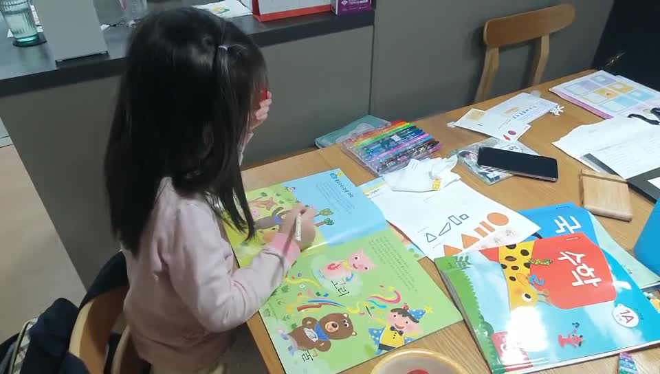 A little child who is studying at a messy table