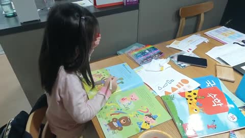 A little child who is studying at a messy table