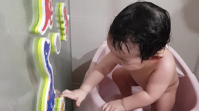 A lovely Korean baby laughing in the shower and the dinosaur toys.