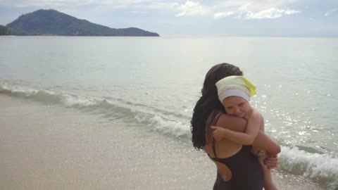 Mom with a daughter walking on the sandy beach