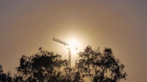 Tower crane during sunset seen in the distance