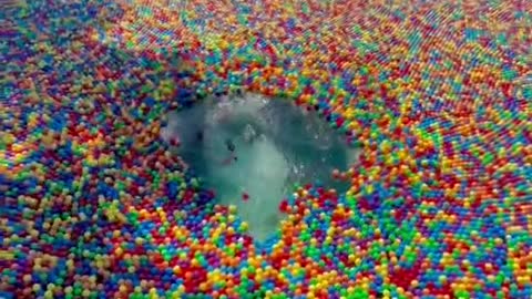 The boy jumped into the water of the rainbow ball