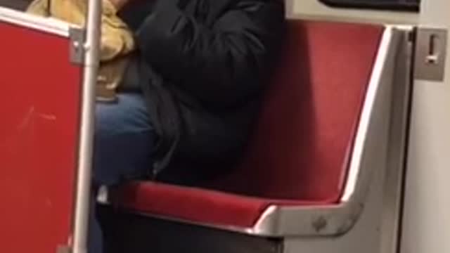 Guy wearing earphones headbangs to music on subway train